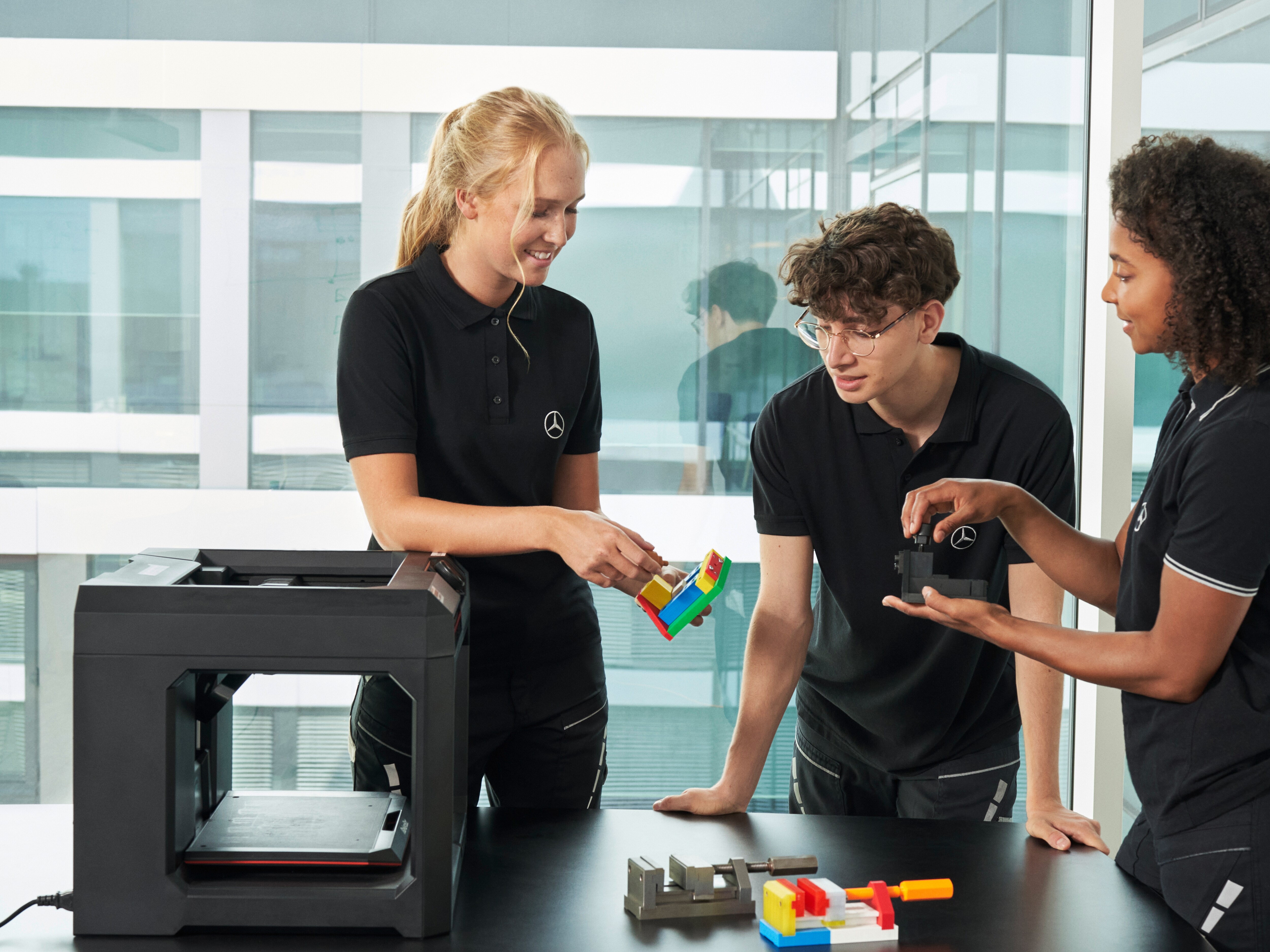 A imagem mostra 3 pessoas trabalhando em um projeto da Mercedes-Benz.