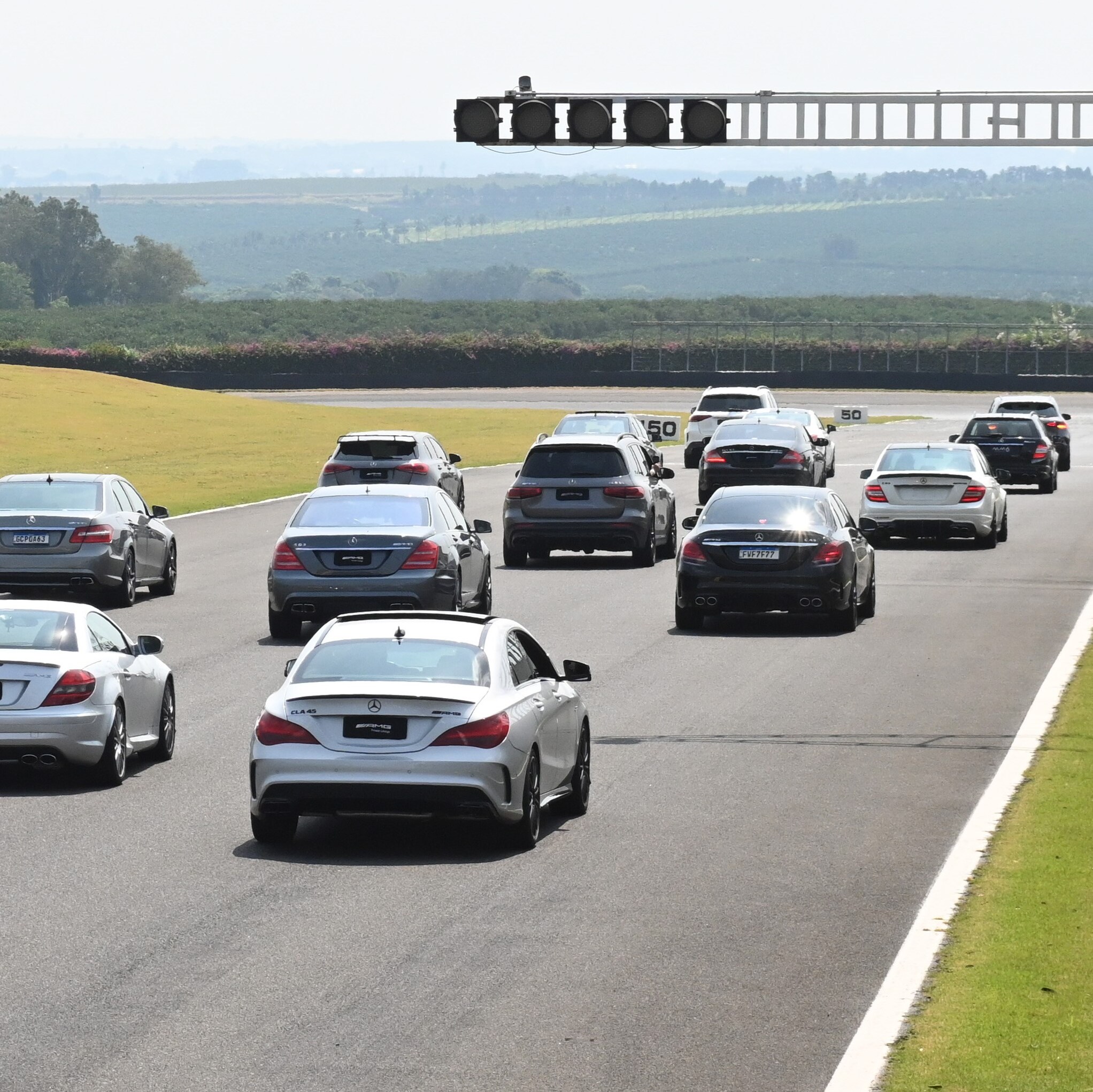 Vários modelos de automóveis Mercedes-Benz em uma pista de corrida.