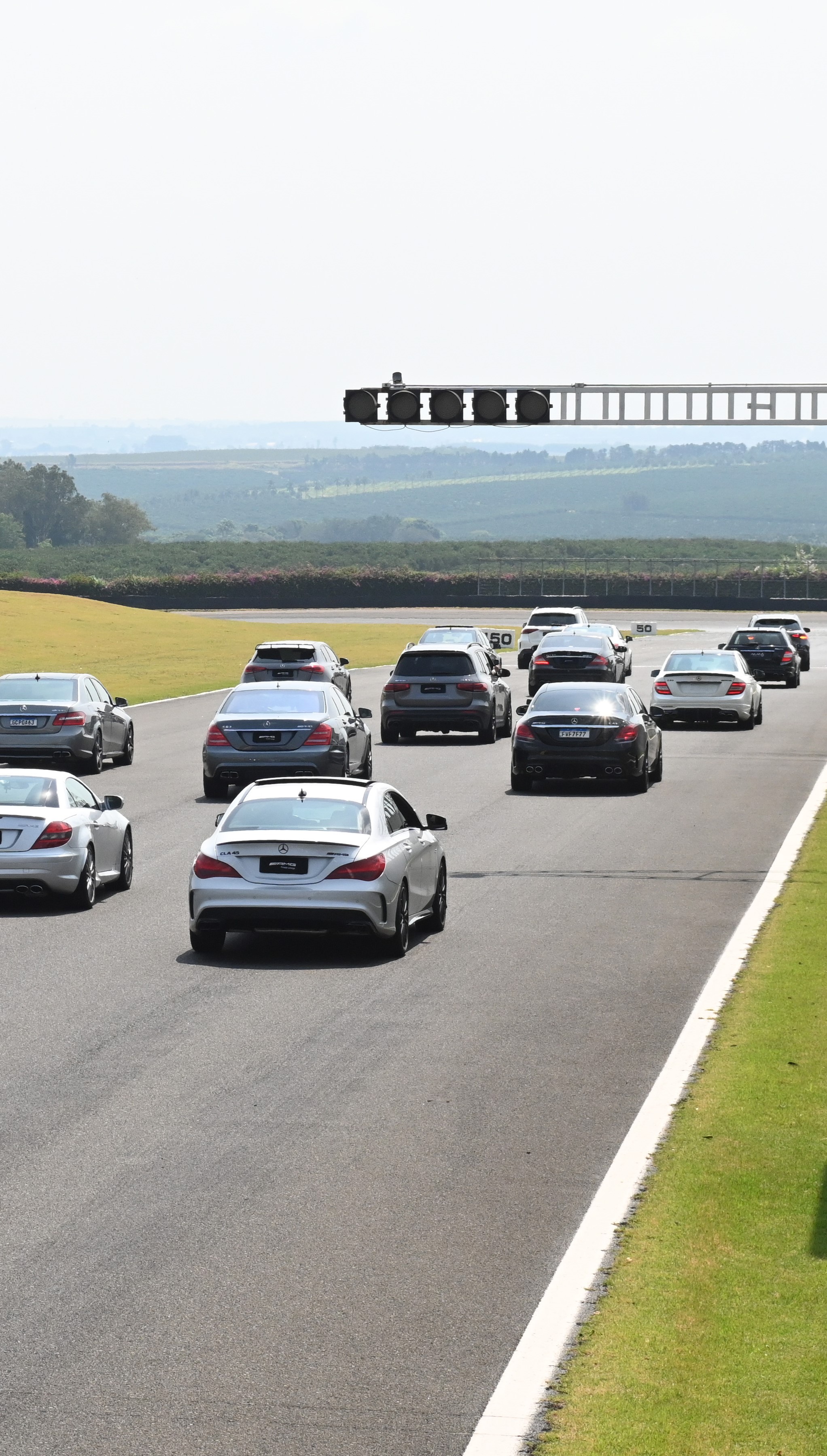 Vários modelos de automóveis Mercedes-Benz em uma pista de corrida.