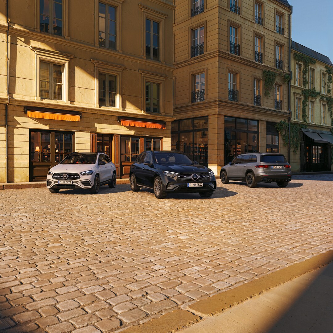 Três modelos Mercedes-Benz em um exterior rústico.