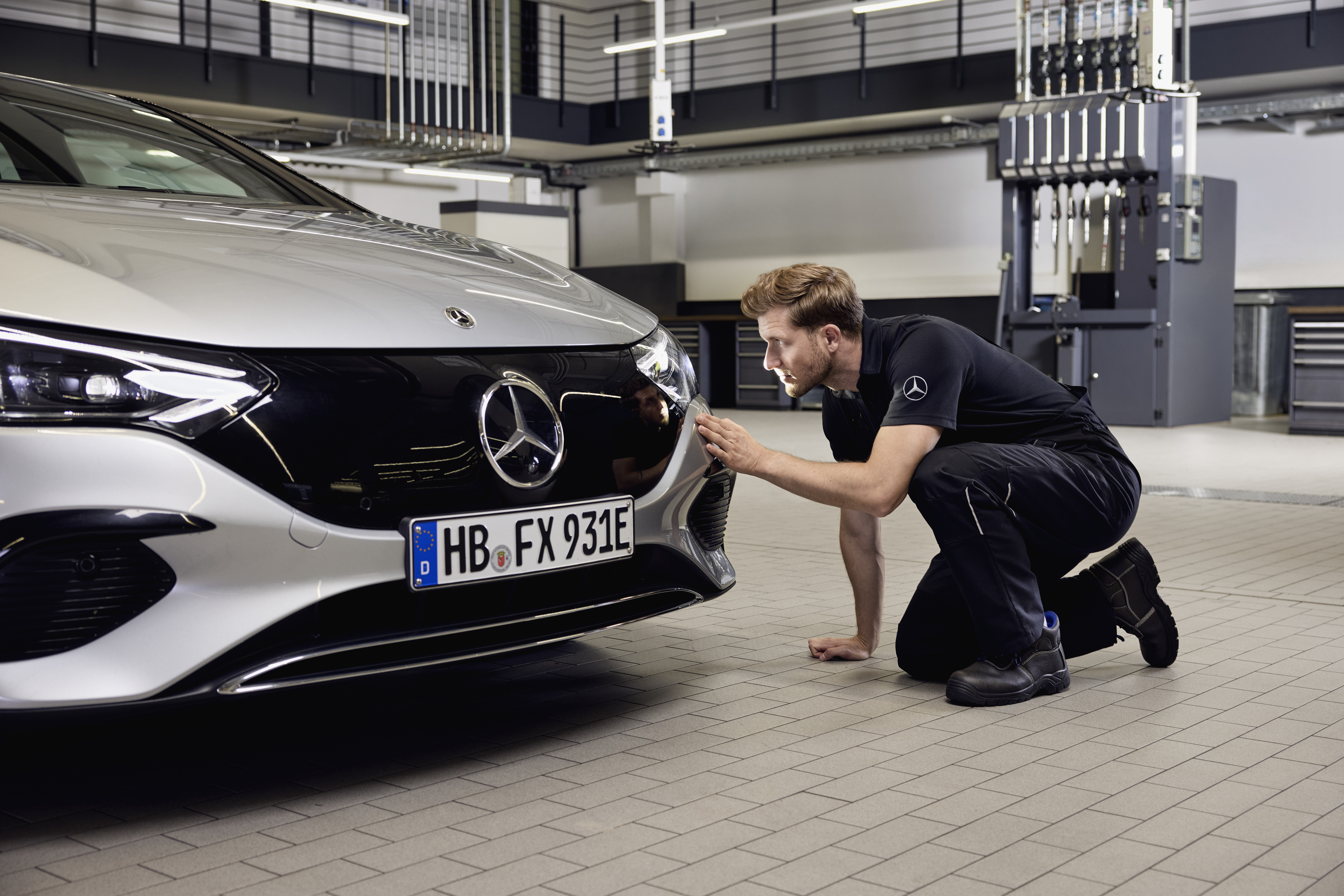 Substituição de faróis genuínos Mercedes-Benz Grande plano da frente de um veículo Mercedes-Benz com um técnico realizando um exame detalhado sobre a substituição de peças genuínas Mercedes-Benz.