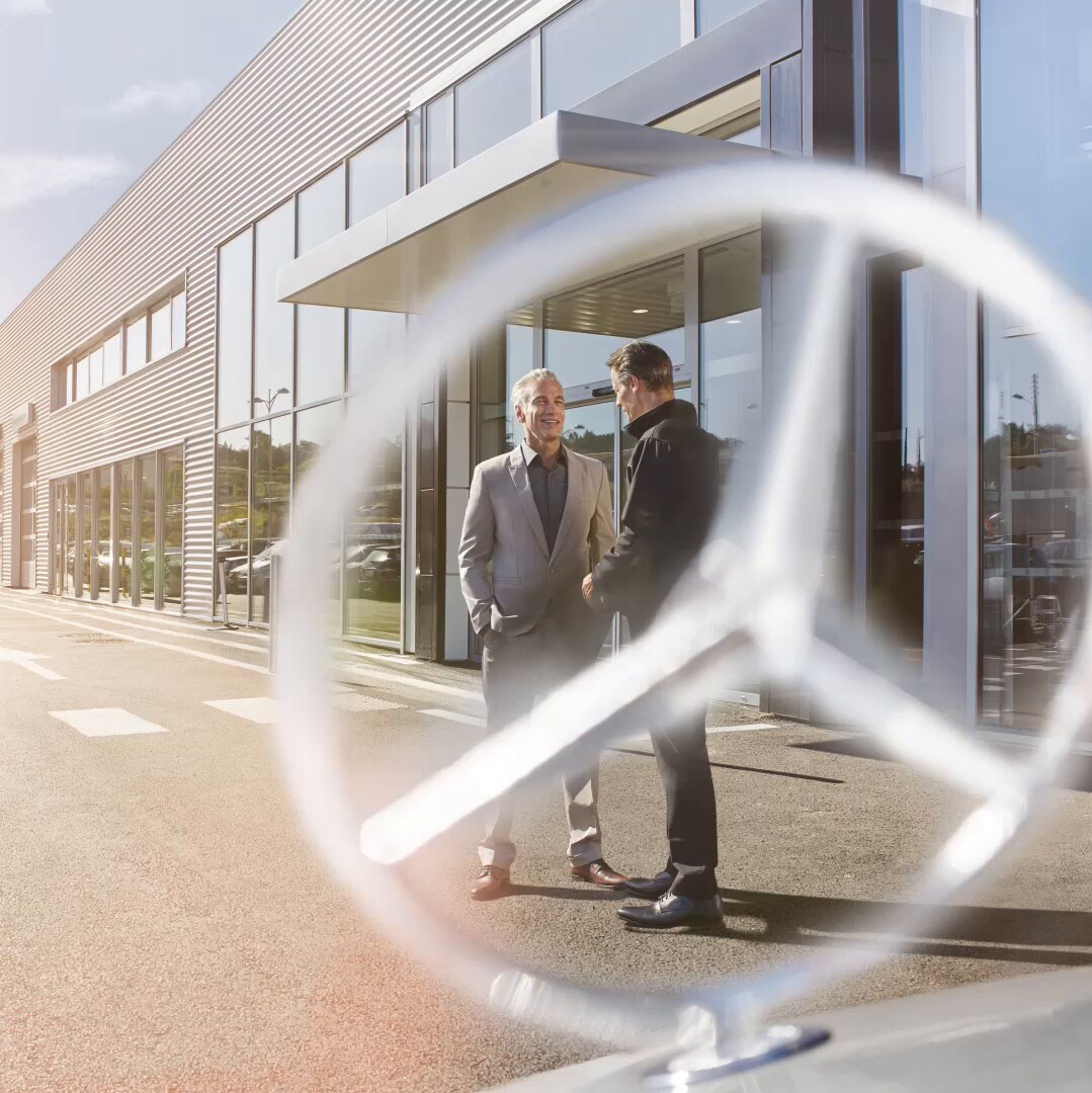 Duas pessoas conversando em frente a estrela de um Mercedes-Benz.