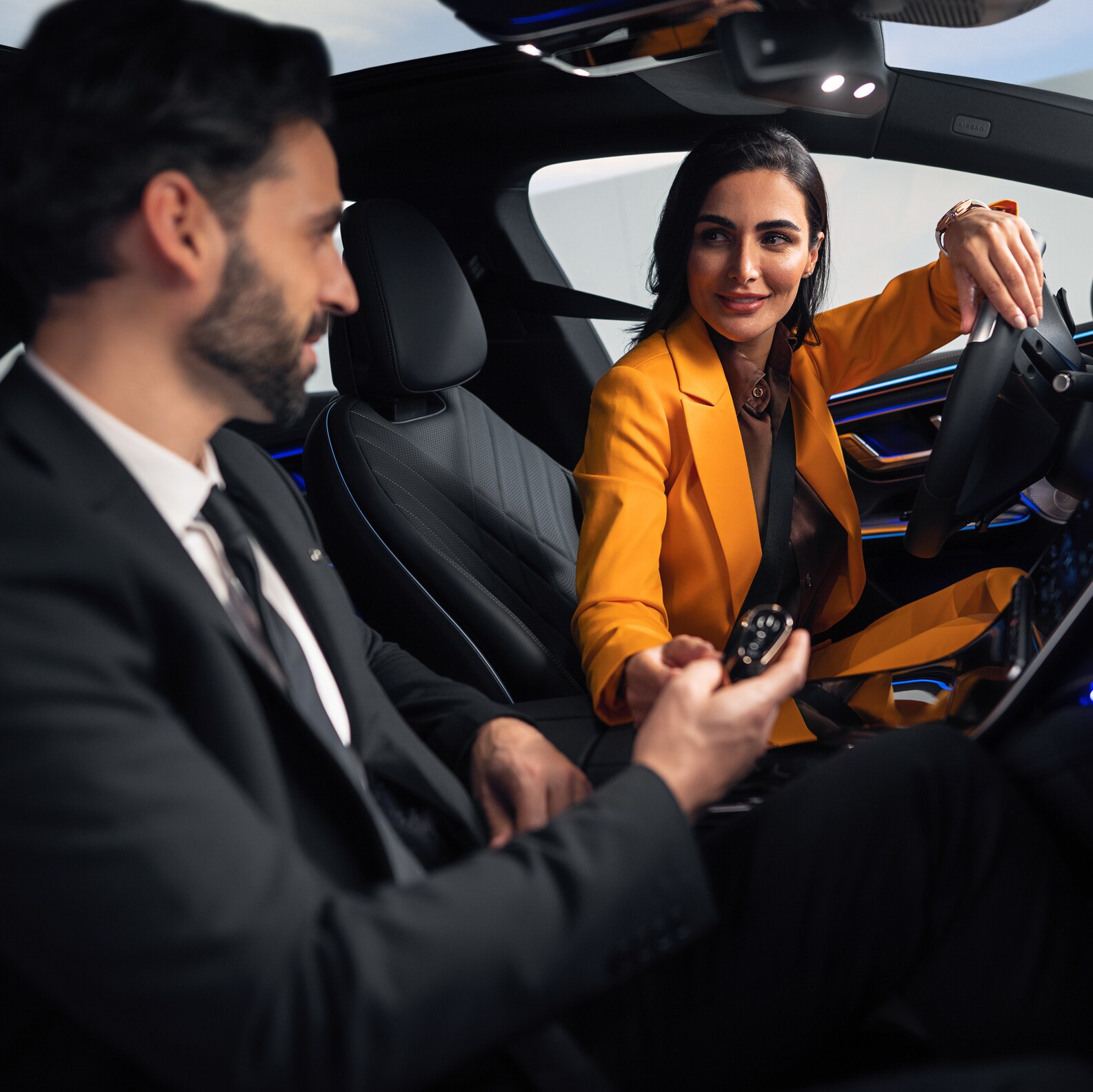 Homem e mulher no banco dianteiro de um Mercedes-Benz.