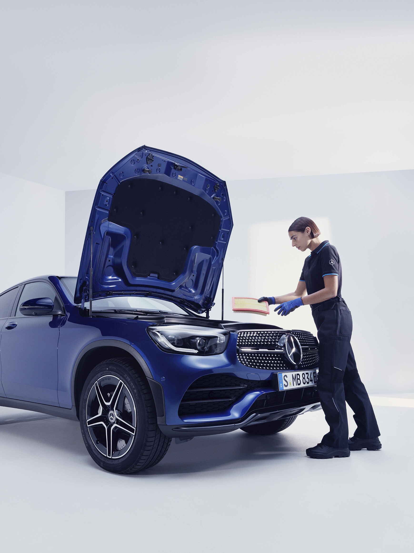 Uma técnica da Mercedes-Benz verificam o compartimento do motor de um veículo.