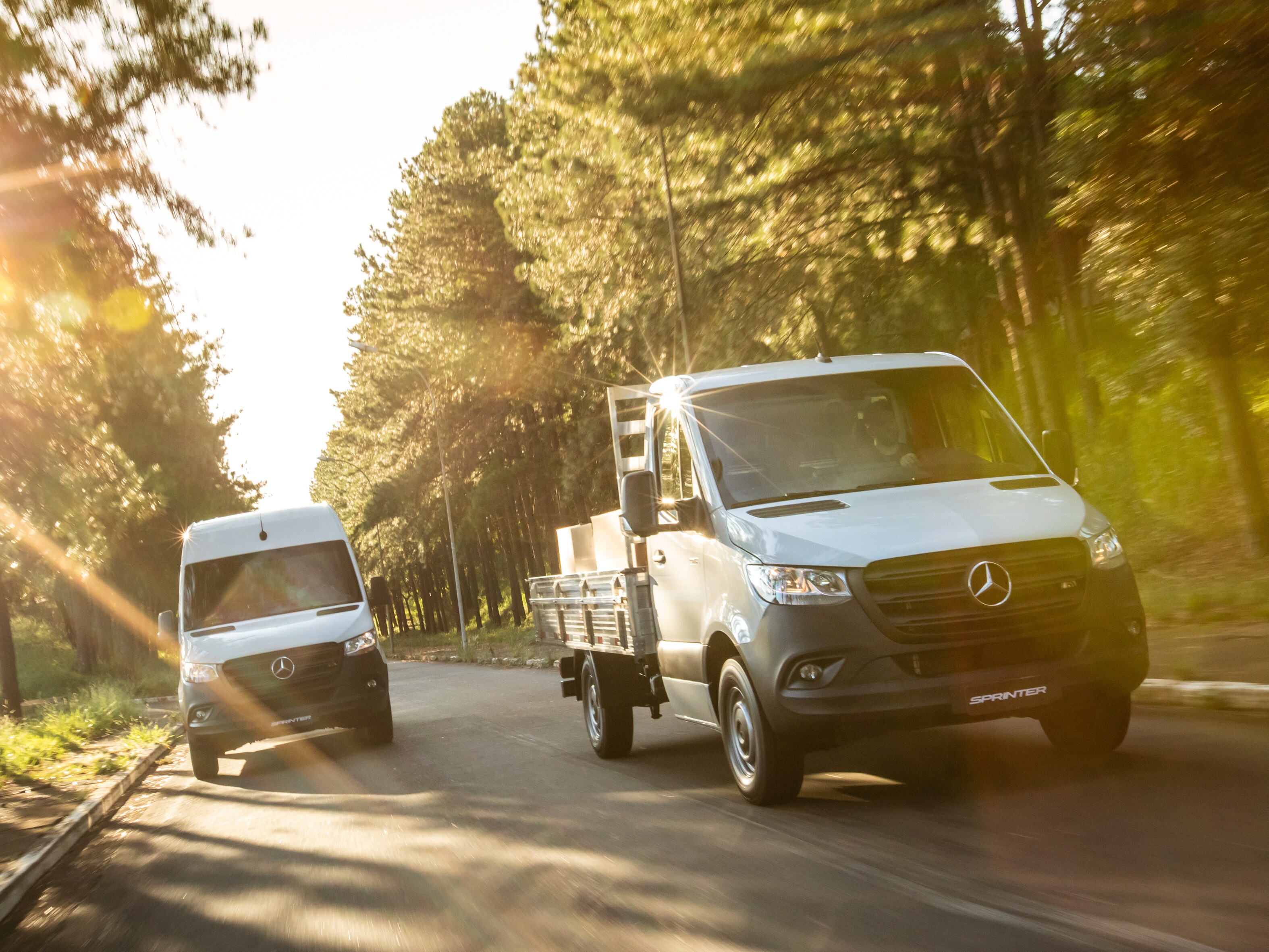 2 modelos Sprinter Mercedes-Benz em uma estrada.
