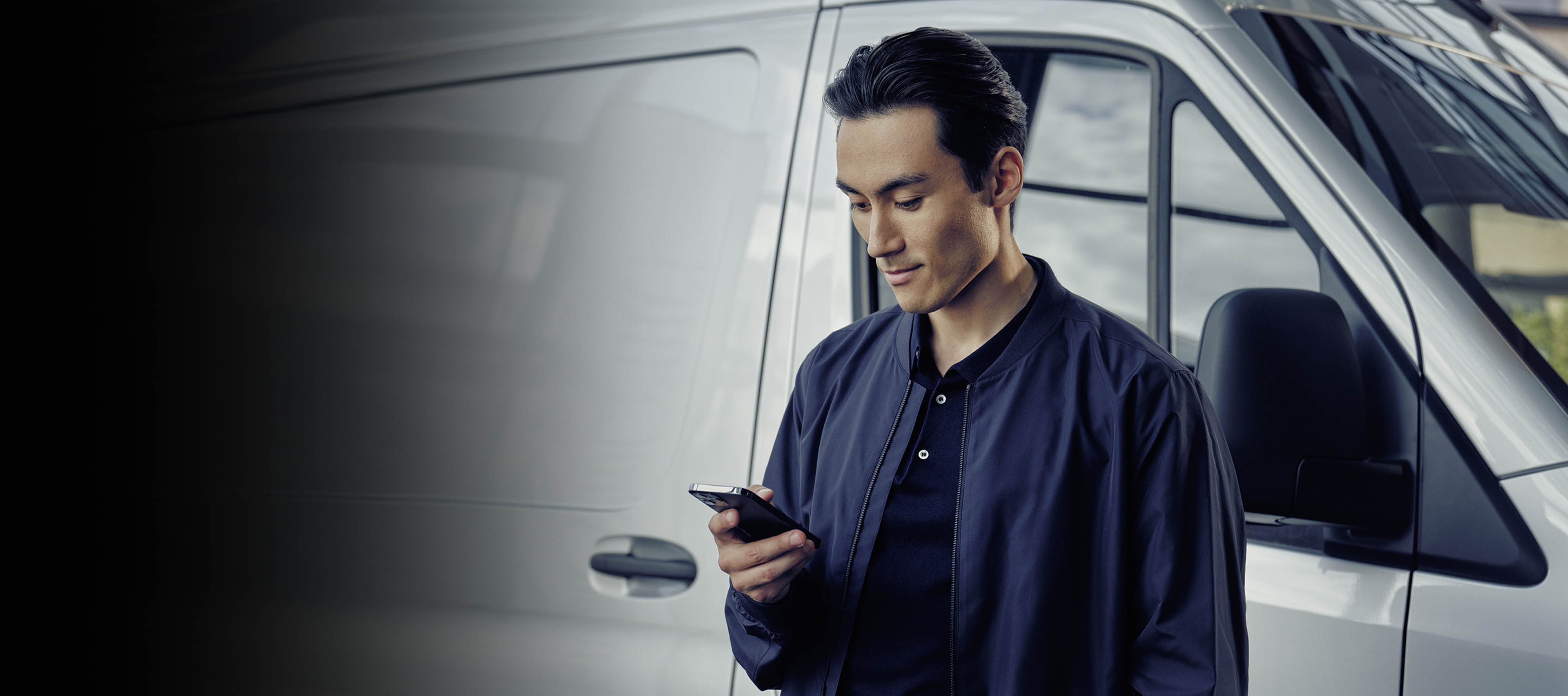 Mercedes-Benz Vans | Consórcio Um homem ao celular em frente a uma van Sprinter.