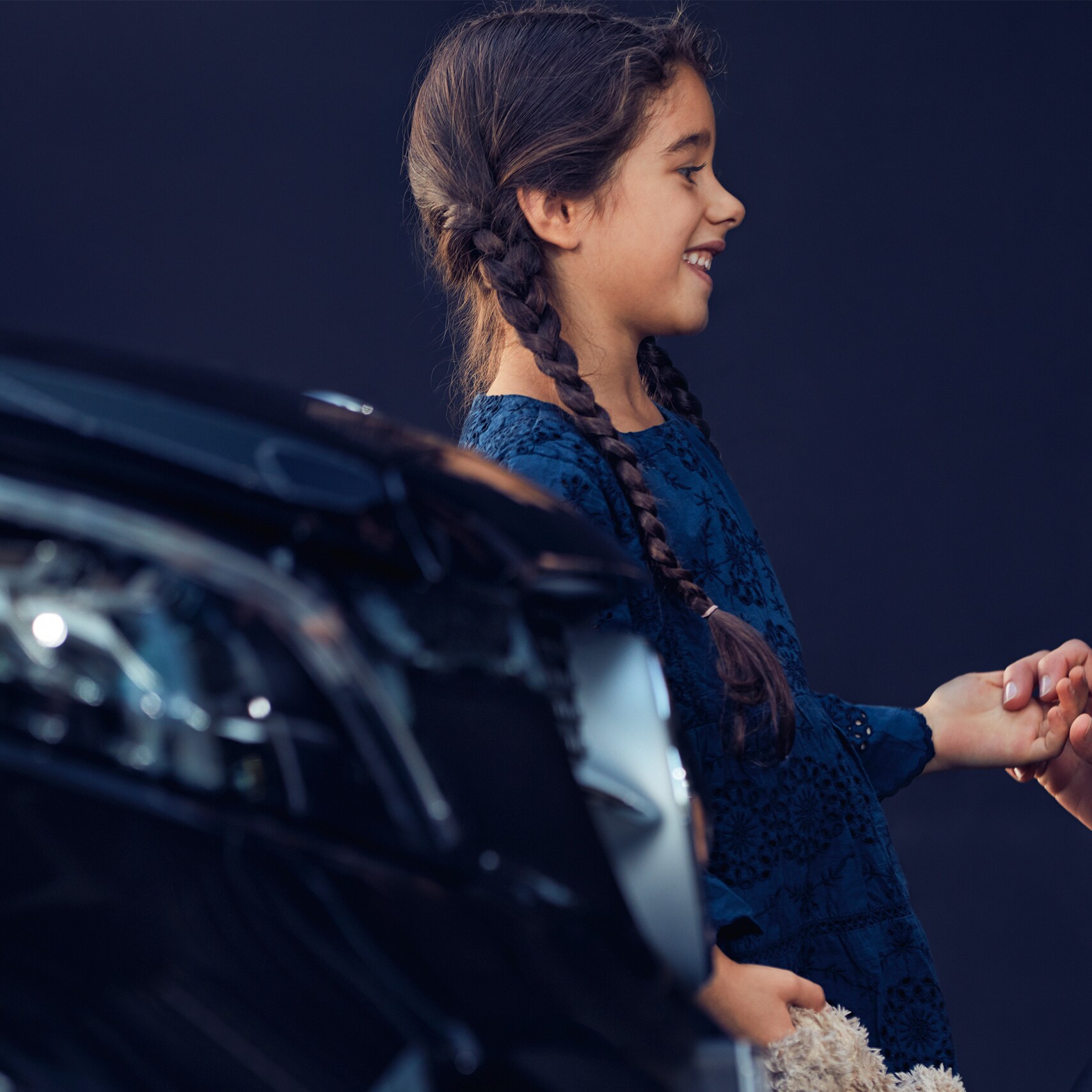 Uma criança e uma mulher diante de um veículo Mercedes-Benz.