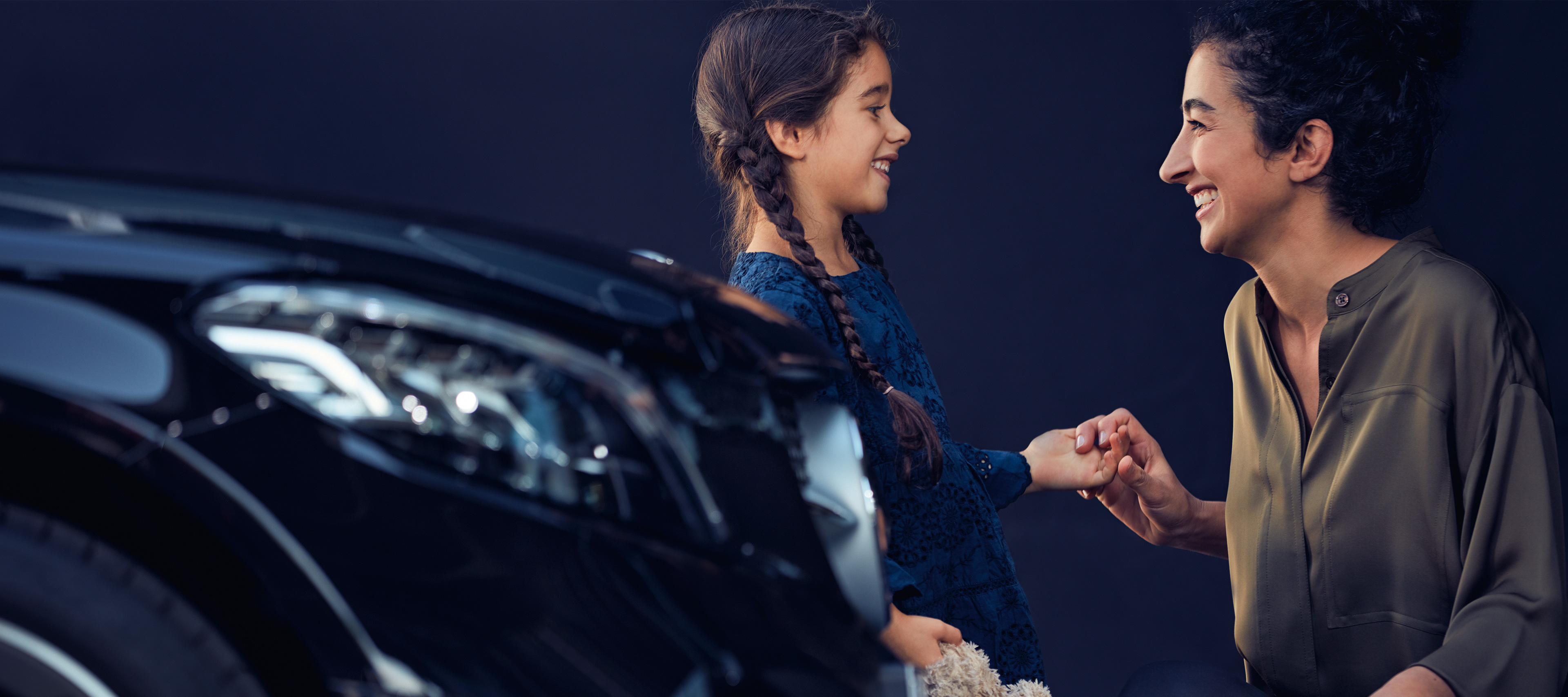 Seguro | Serviços Financeiros| Mercedes-Benz Uma criança e uma mulher diante de um veículo Mercedes-Benz.