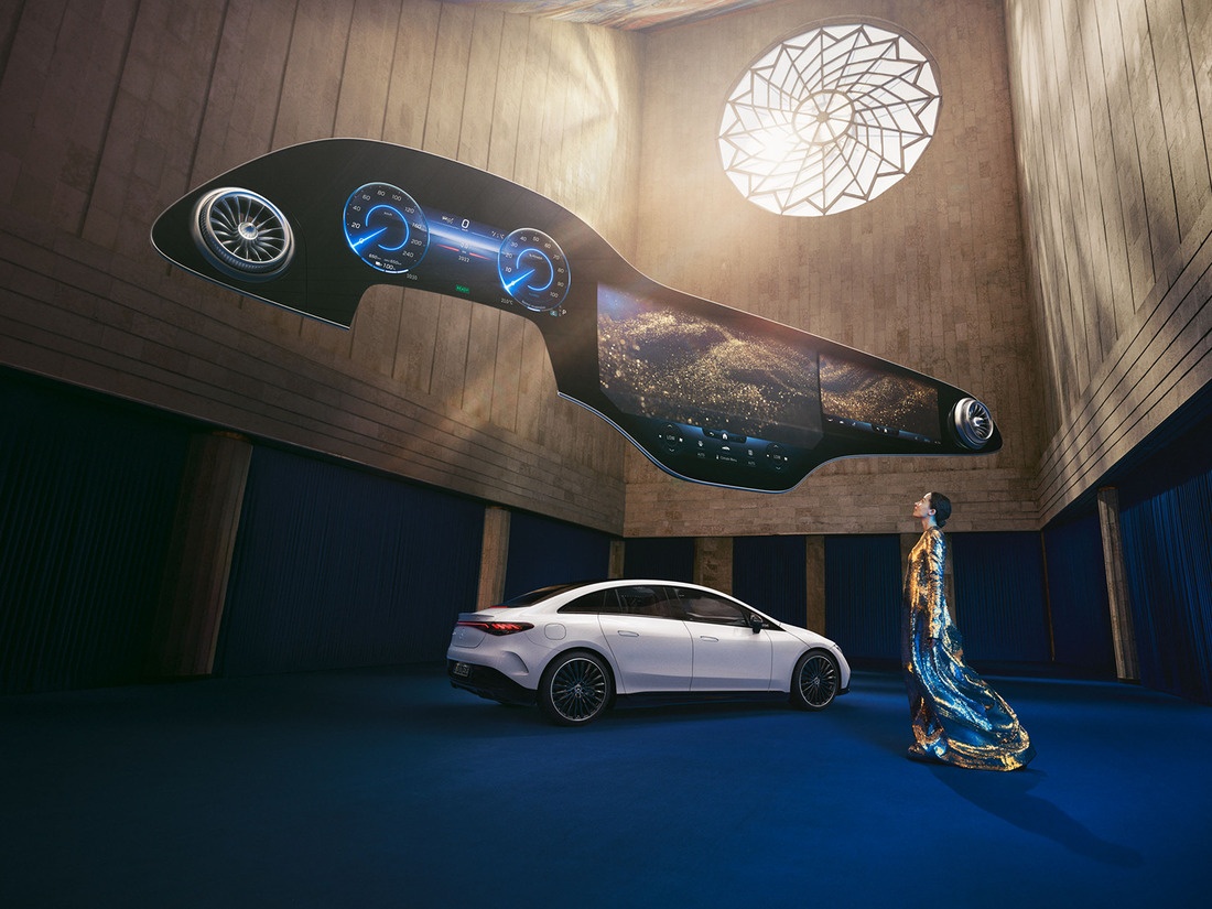 Mulher de pé na frente do veículo Mercedes-Benz EQ com o Hyperscreen flutuando sobre ela. Mercedes-Benz Hyperscreen
