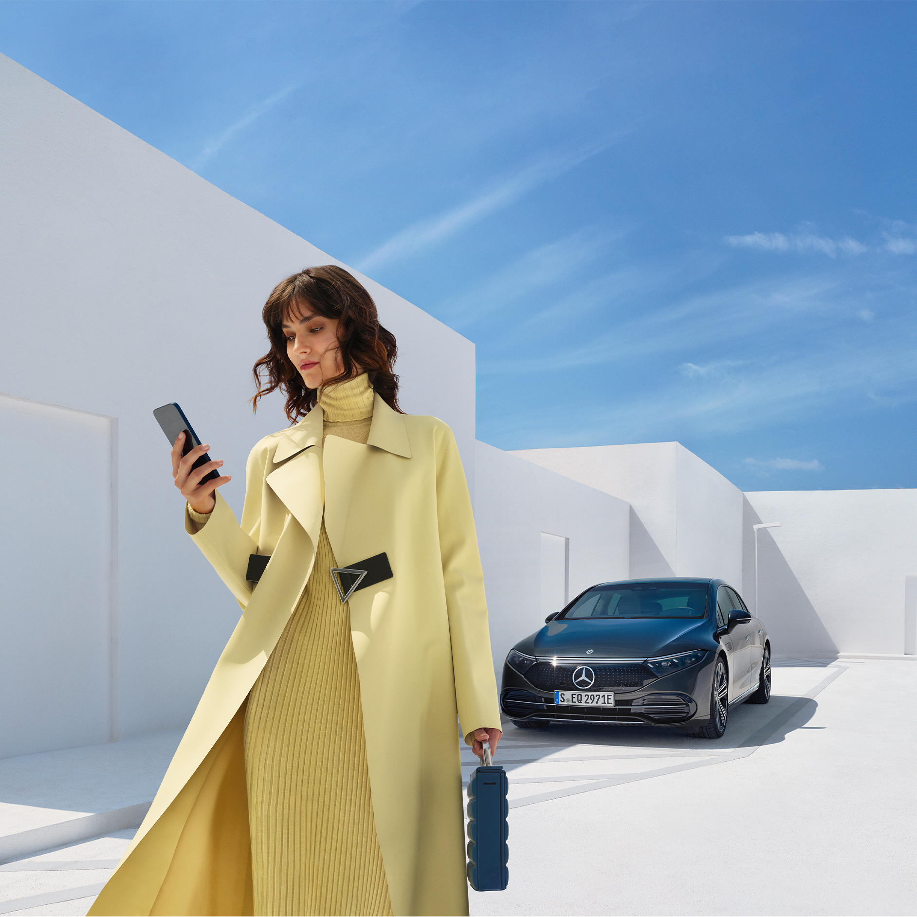 Comprar funcionalidades digitais extras | Entretenimento | Mercedes-Benz Uma mulher olha para o seu celular enquanto se afasta do seu veículo Mercedes-Benz com tecnologia EQ.