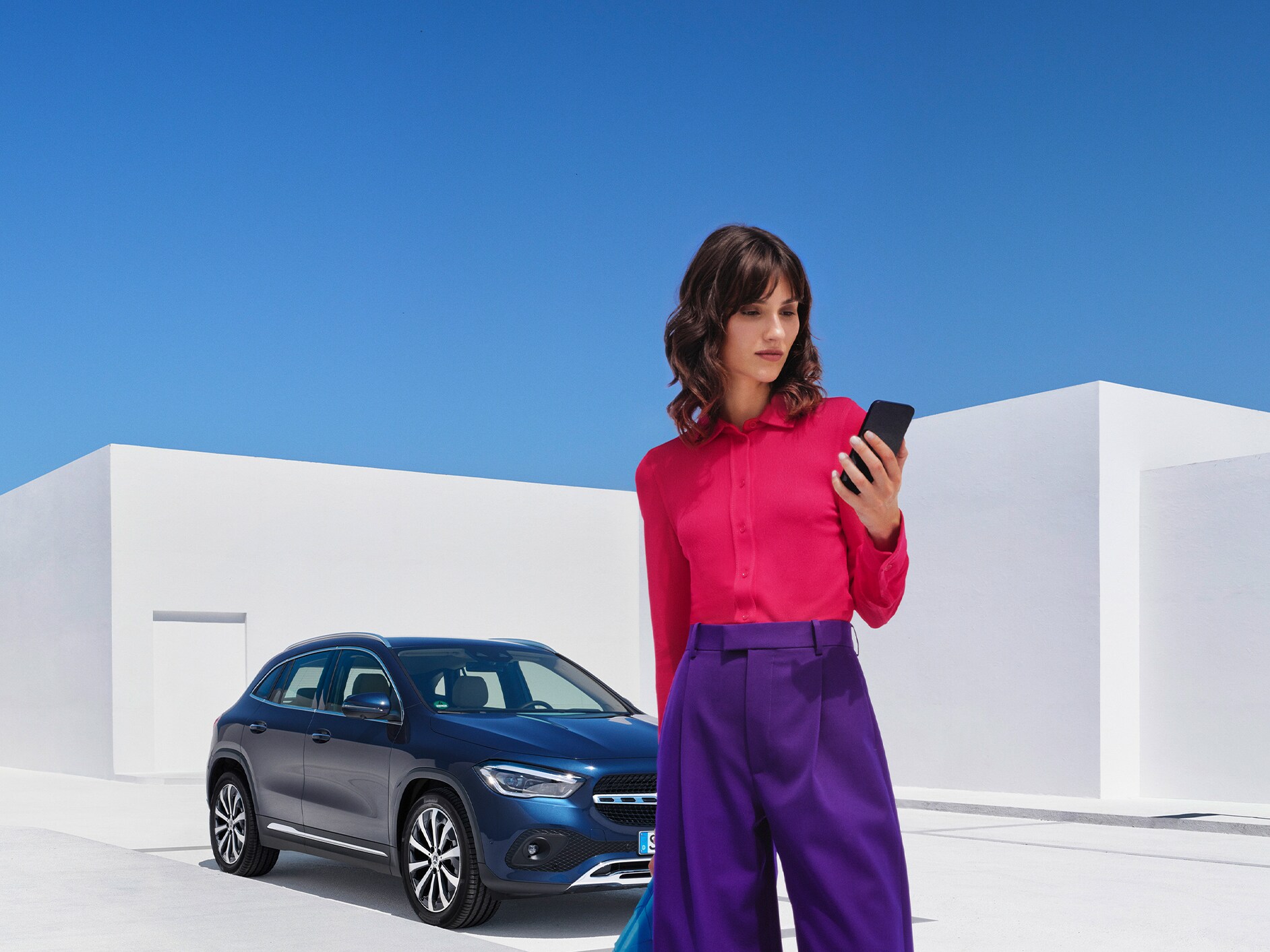 Uma mulher se conecta ao seu Mercedes-Benz pelo Mercedes me App no seu smartphone.