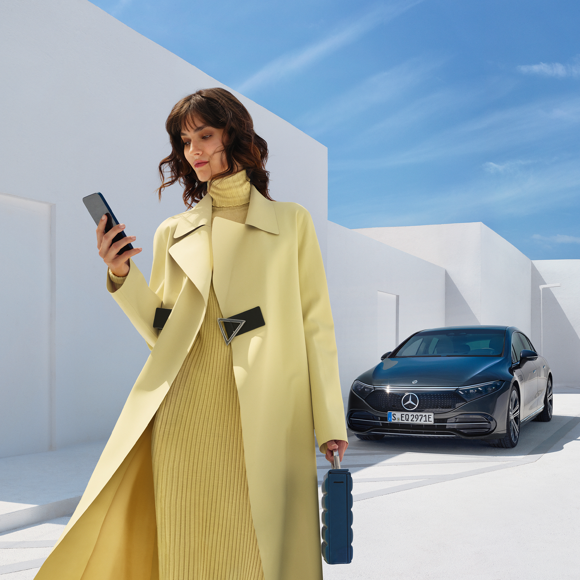 Comprar funcionalidades digitais extras | Serviços Remotos | Mercedes-Benz A imagem apresenta uma mulher na frente do EQS Sedan da Mercedes-Benz.