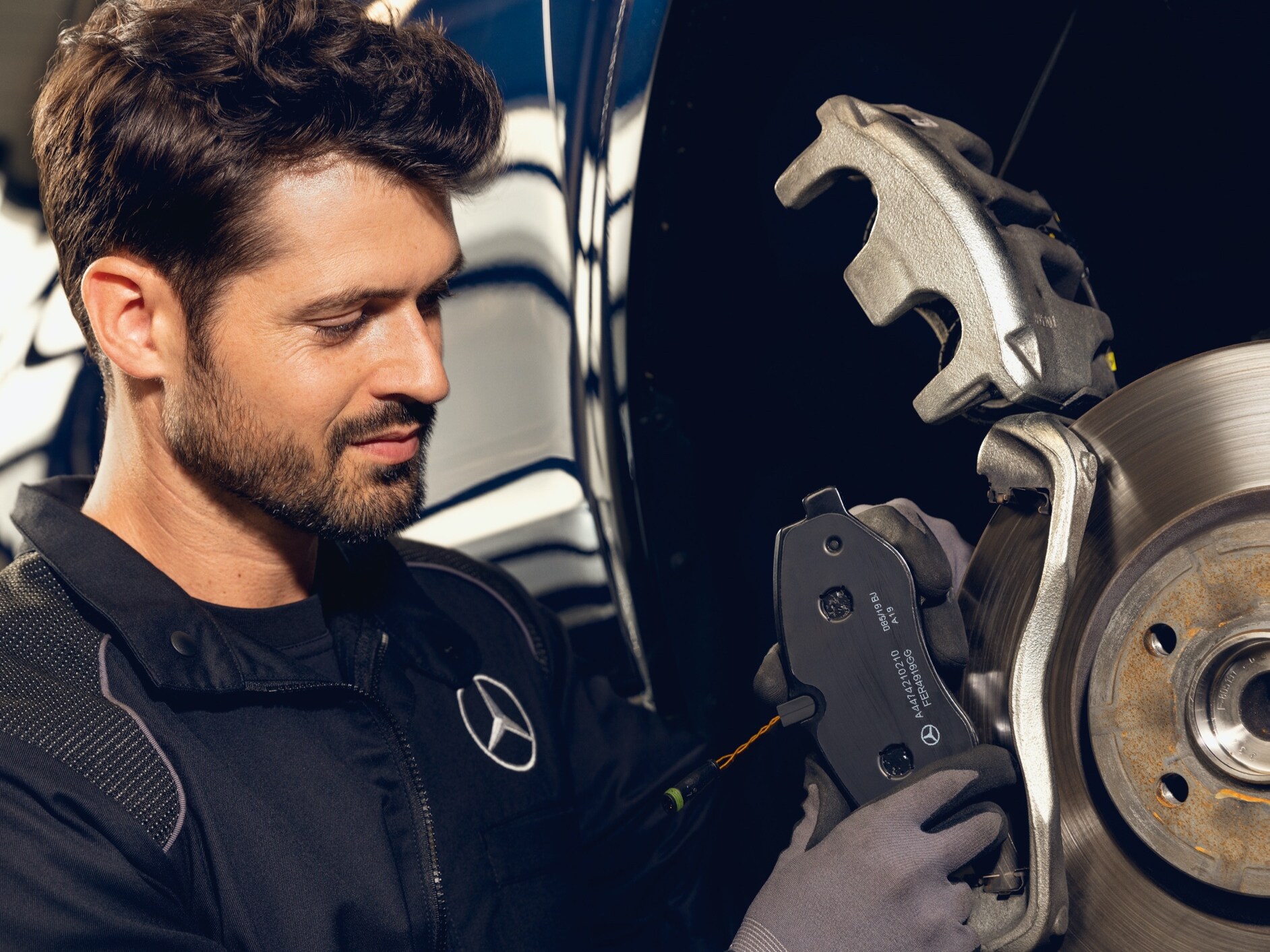 Um homem fazendo uma manutenção em um automóvel Mercedes-Benz.