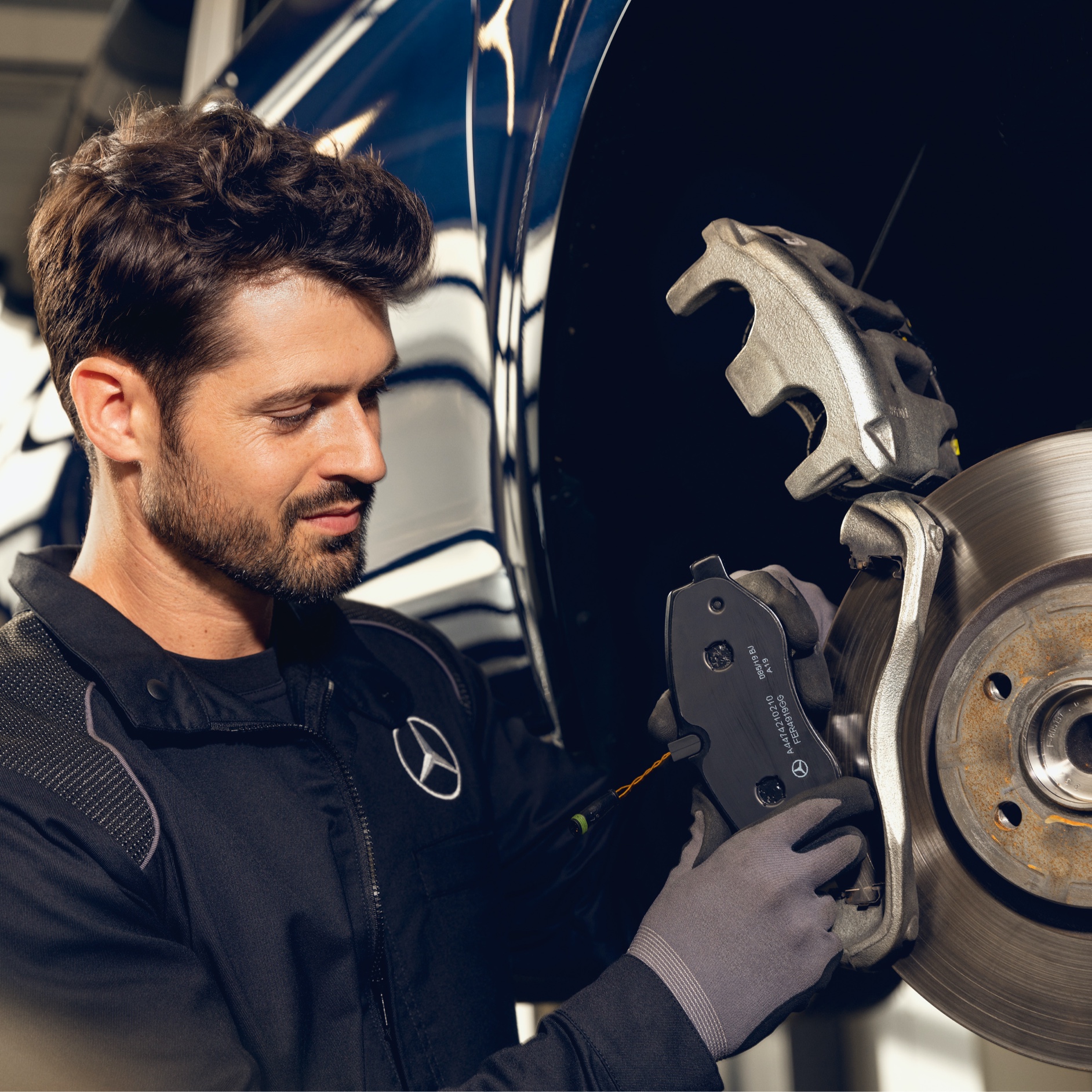Peças genuínas | Mercedes-Benz Um homem fazendo uma manutenção em um automóvel Mercedes-Benz.