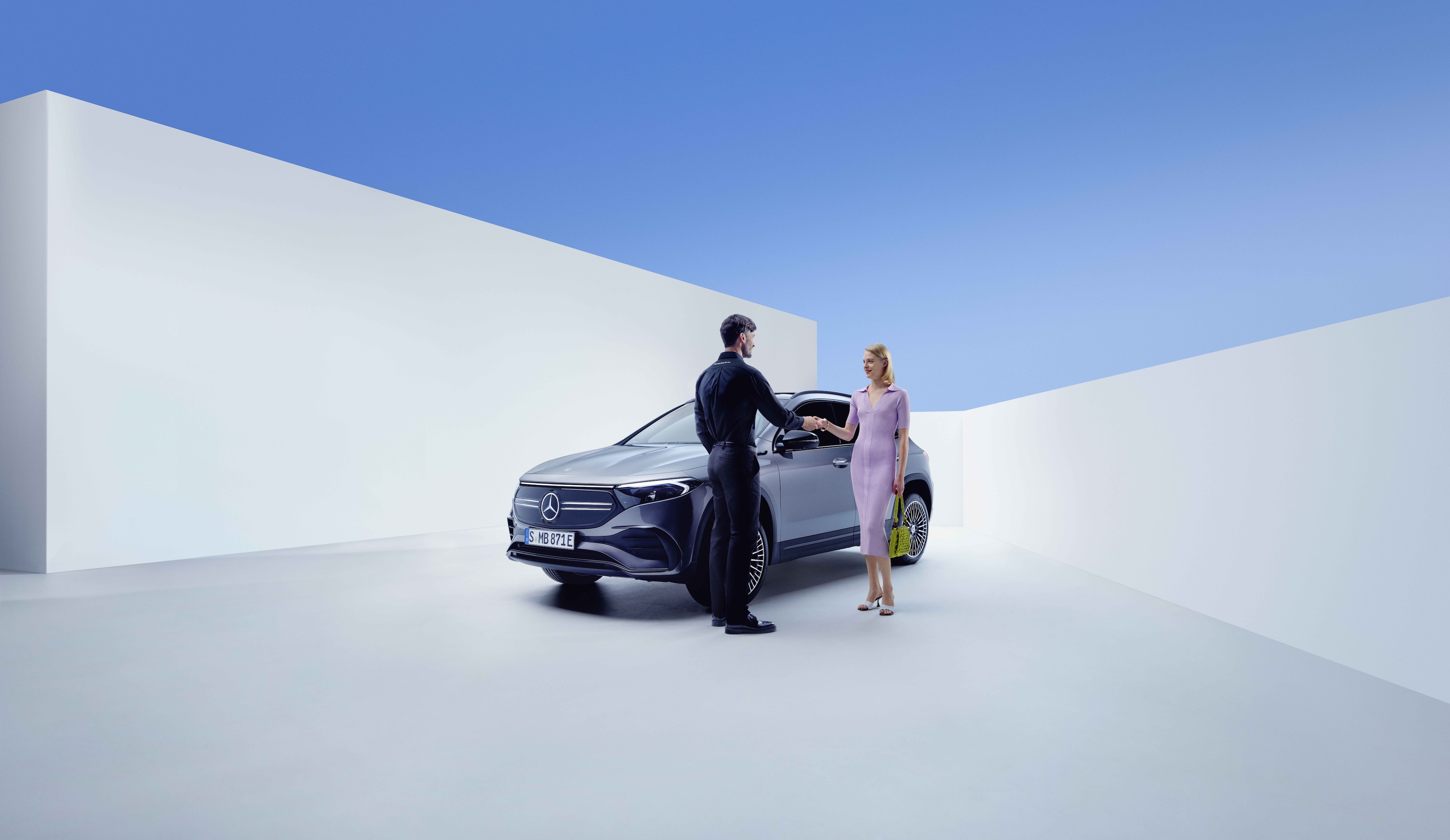 Serviço e Reparo | Mercedes-Benz Aperto de mão entre um funcionário da Mercedes-Benz e uma mulher, diante de um Mercedes-Benz