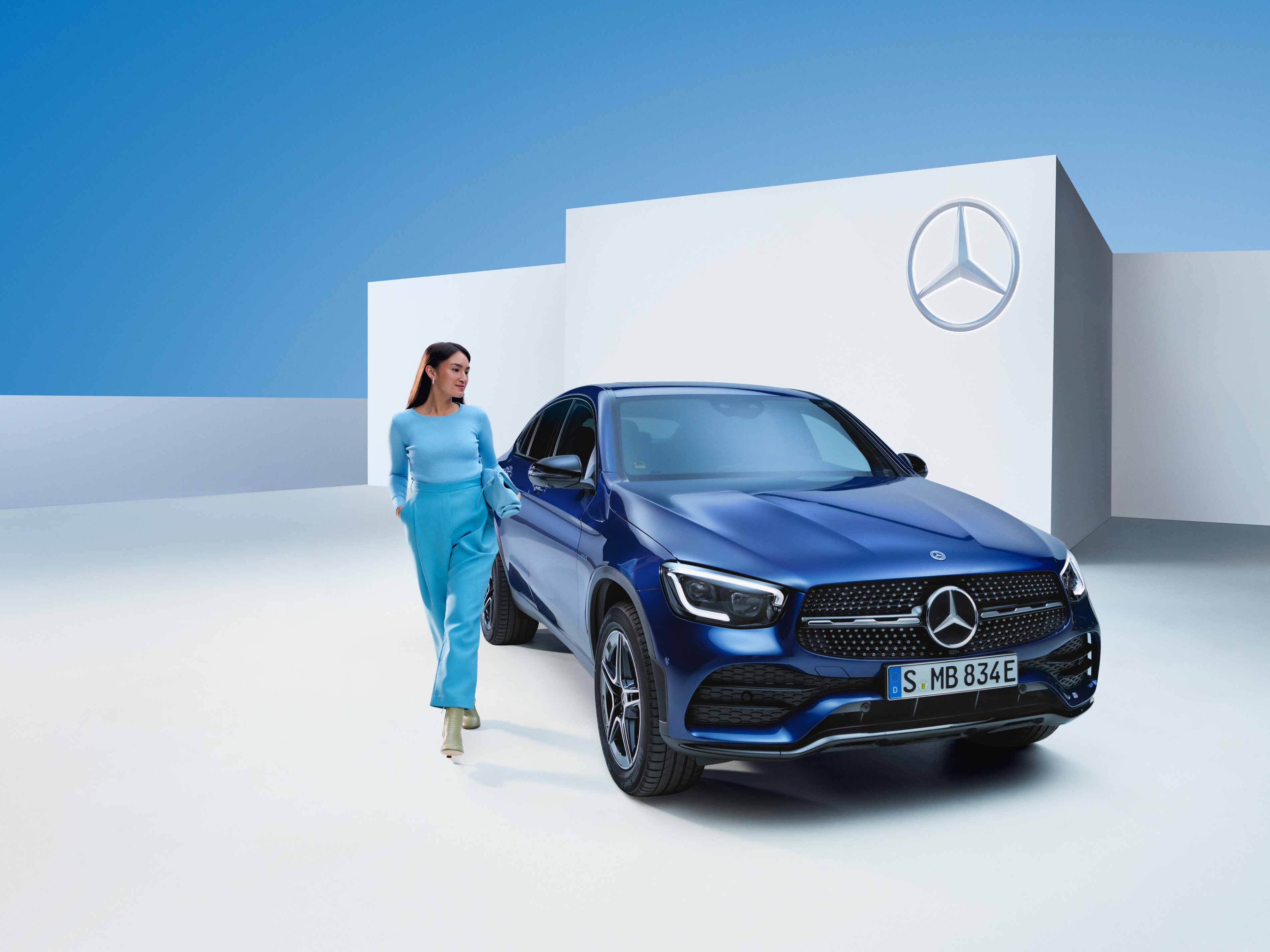Uma mulher caminha ao lado de seu Mercedes-Benz.