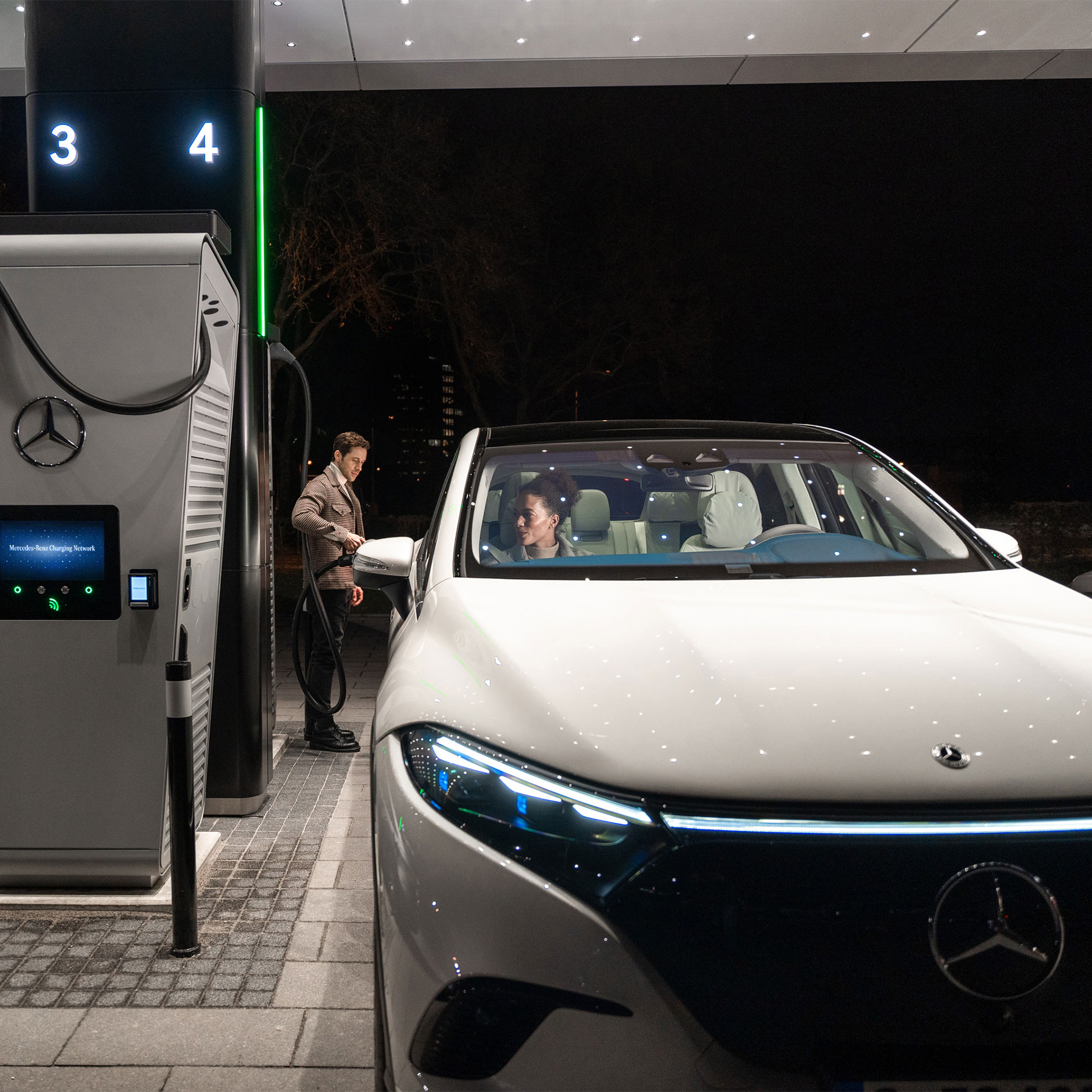 Carregamento público | Carregamento | Mercedes-Benz Uma pessoa que carrega um Mercedes-Benz EQS SUV em uma estação de carga.