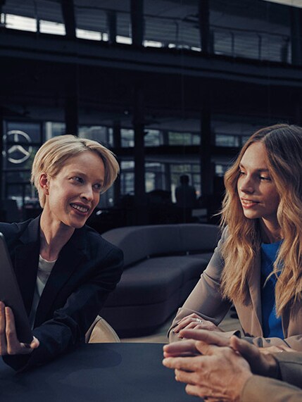 Um grupo de pessoas sentadas em frente a uma filial Mercedes-Benz.